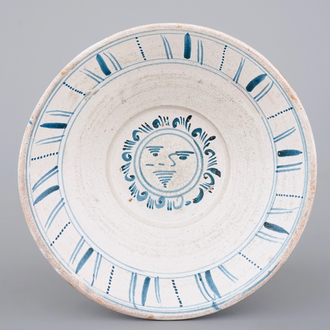 A large Spanish blue and white faience bowl with a sun face, 19th C.
